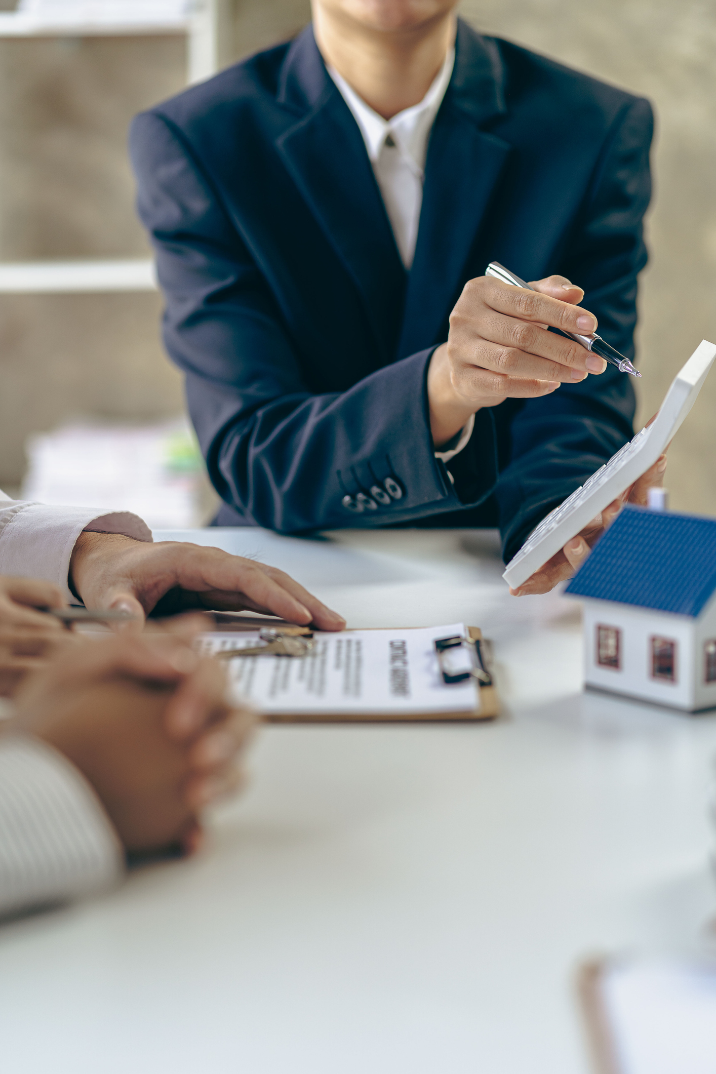 An agent and client with a contract and calculator | Reverse Mortgage FAQ